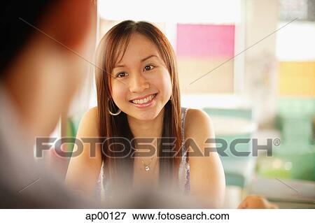 Young woman facing another person, smiling, over the shoulder view View Large Photo Image Stock Photo - Young woman facing another person, smiling, over the shoulder view. Fotosearch