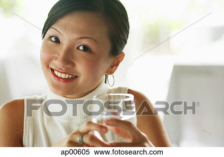 Stock Photography - Young woman holding glass of water, portrait. Fotosearch