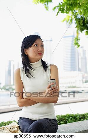 Young woman, holding mobile phone, arms crossed View Large Photo Image Stock Photography - Young woman, holding mobile phone, arms crossed. Fotosearch