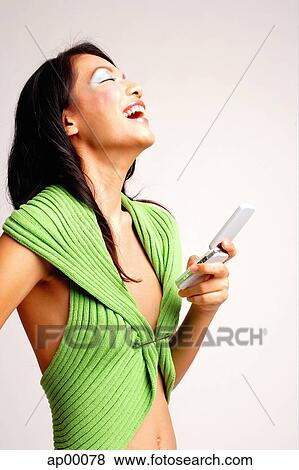Young woman holding mobile phone, laughing View Large Photo Image Stock Photo - Young woman holding mobile phone, laughing. Fotosearch