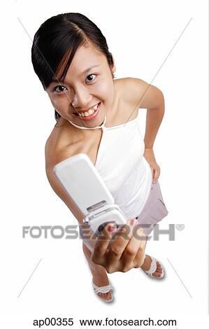 Young woman holding mobile phone, looking at camera View Large Photo Image Stock Photography - Young woman holding mobile phone, looking at camera. Fotosearch