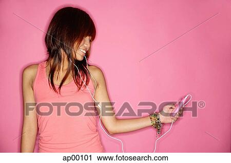 Young woman holding mp3 player, looking away View Large Photo Image Stock Image - Young woman holding mp3 player, looking away. Fotosearch