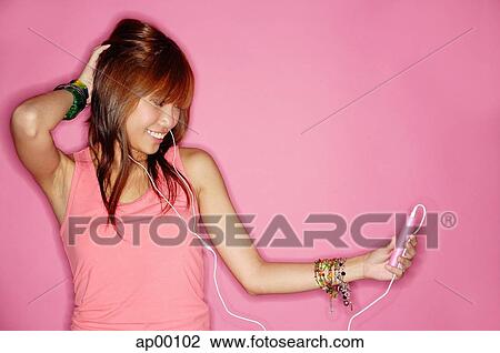 Stock Image - Young woman holding mp3 player, looking away, hand behind head. Fotosearch