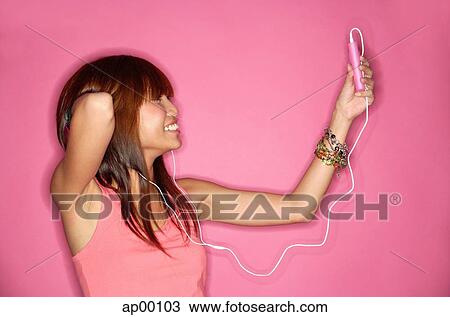 Stock Image - Young woman holding mp3 player, looking up, hand behind head. Fotosearch
