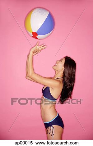 Young woman in bikini, tossing beach ball, side view View Large Photo Image Stock Photography - Young woman in bikini, tossing beach ball, side view. Fotosearch
