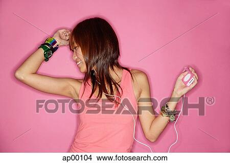 Picture - Young woman listening to mp3 player, portrait. Fotosearch