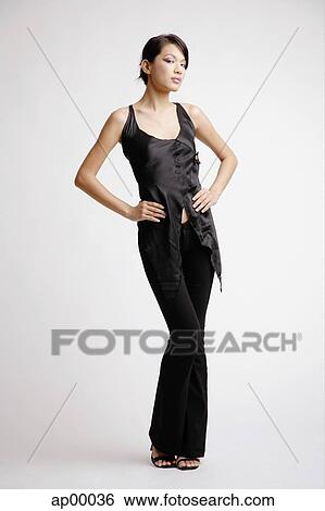 Stock Photograph - Young woman looking at camera, hands on hips. Fotosearch