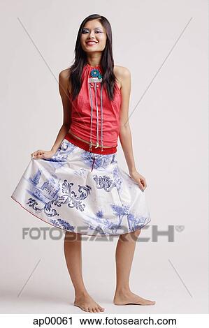 Young woman, looking at camera, smiling, holding skirt View Large Photo Image Stock Image - Young woman, looking at camera, smiling, holding skirt. Fotosearch