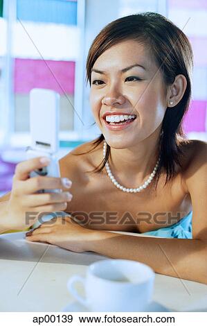 Young woman looking at mobile phone View Large Photo Image Stock Photo - Young woman looking at mobile phone. Fotosearch