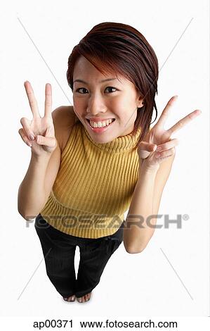 Stock Image - Young woman looking up at camera, making hand sign. Fotosearch