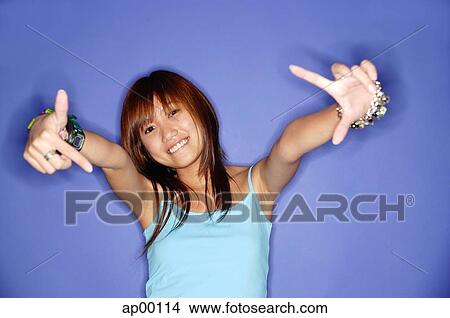 Young woman making hand signs, looking at camera, smiling View Large Photo Image Picture - Young woman making hand signs, looking at camera, smiling. Fotosearch