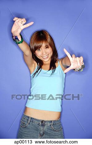 Stock Image - Young woman making hand signs, looking at camera. Fotosearch