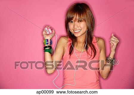 Stock Photo - Young woman smiling, listening to mp3 player. Fotosearch