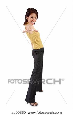 Stock Image - Young woman standing, hand outstretched towards camera. Fotosearch