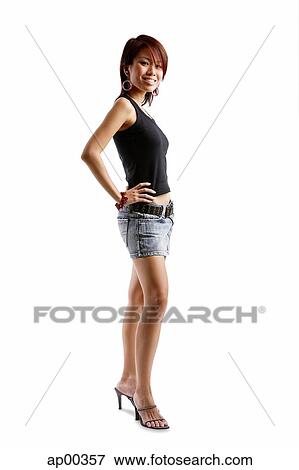 Young woman standing with hands on hips, looking at camera View Large Photo Image Stock Photo - Young woman standing with hands on hips, looking at camera. Fotosearch