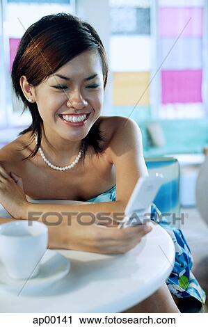 Stock Image - Young woman using mobile phone. Fotosearch