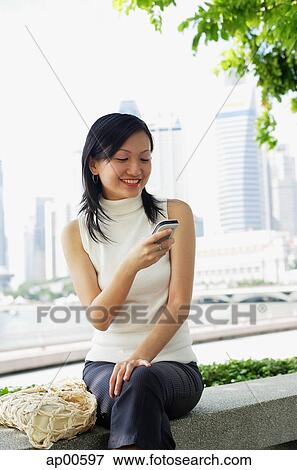 Young woman, using mobile phone, text messaging View Large Photo Image Stock Photo - Young woman, using mobile phone, text messaging. Fotosearch