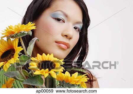 Stock Photo - Young woman, with bouquet of sunflowers, looking at camera. Fotosearch