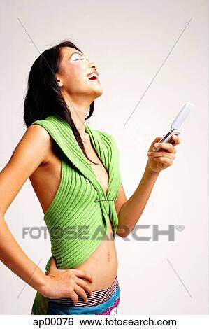 Young woman with mobile phone, hand on hip, laughing View Large Photo Image Stock Photograph - Young woman with mobile phone, hand on hip, laughing. Fotosearch