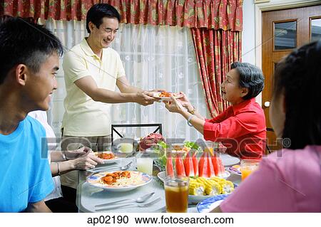 Adult son passing plate of food to senior woman View Large Photo Image Stock Image - Adult son passing plate of food to senior woman . Fotosearch