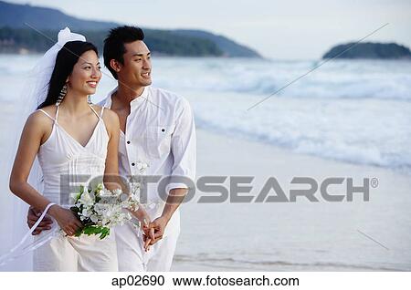 Bride and groom standing on beach, holding hands, looking away View Large Photo Image Stock Image - Bride and groom standing on beach, holding hands, looking away. Fotosearch
