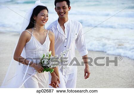 Bride and groom walking on beach, smiling View Large Photo Image Stock Photo - Bride and groom walking on beach, smiling . Fotosearch
