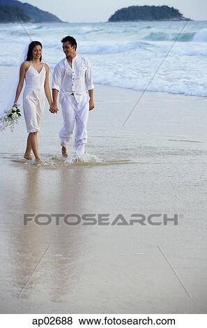 Bride and groom walking on beach, holding hands View Large Photo Image Stock Photo - Bride and groom walking on beach, holding hands . Fotosearch