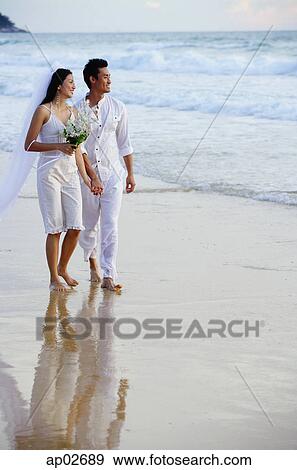 Bride and groom walking on beach, looking out to sea View Large Photo Image Stock Photo - Bride and groom walking on beach, looking out to sea. Fotosearch