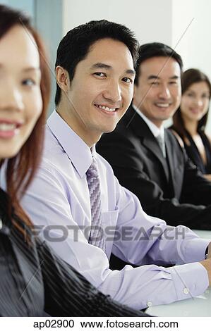 Business people sitting in a row, smiling at camera View Large Photo Image Stock Image - Business people sitting in a row, smiling at camera . Fotosearch