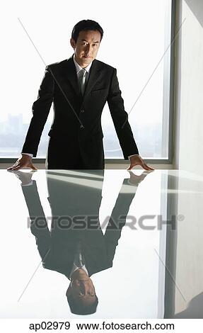 Businessman leaning on table, looking at camera View Large Photo Image Stock Photo - Businessman leaning on table, looking at camera . Fotosearch