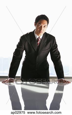Businessman leaning on table, looking at camera View Large Photo Image Stock Photography - Businessman leaning on table, looking at camera . Fotosearch