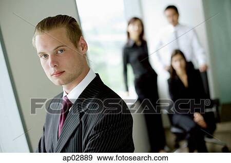 Businessman looking at camera, people in the background View Large Photo Image Stock Photo - Businessman looking at camera, people in the background . Fotosearch