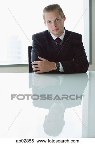 Businessman sitting at table, arms crossed, looking at camera View Large Photo Image Stock Photography - Businessman sitting at table, arms crossed, looking at camera . Fotosearch