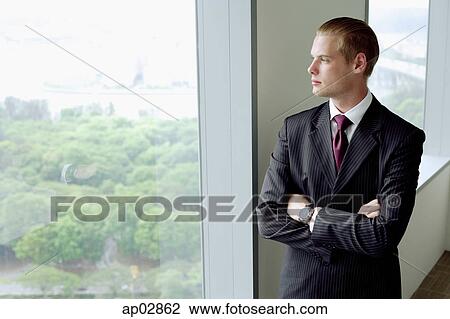 Businessman standing next to window in conference room, arms crossed View Large Photo Image Stock Image - Businessman standing next to window in conference room, arms crossed . Fotosearch