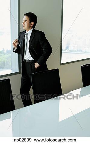 Businessman standing next to window in conference room View Large Photo Image Stock Photo - Businessman standing next to window in conference room . Fotosearch