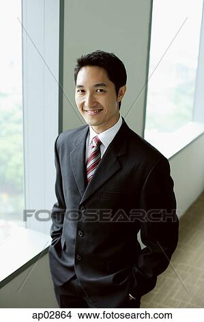Businessman standing next to window, hands in pocket View Large Photo Image Picture - Businessman standing next to window, hands in pocket . Fotosearch
