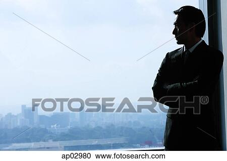 Stock Image - Businessman standing next to window, looking out . Fotosearch