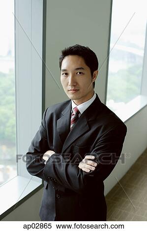 Businessman standing next to window, arms crossed, looking at camera View Large Photo Image Stock Photography - Businessman standing next to window, arms crossed, looking at camera . Fotosearch