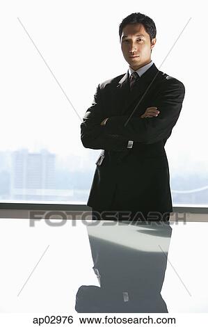 Businessman standing with arms crossed, looking at camera View Large Photo Image Stock Photograph - Businessman standing with arms crossed, looking at camera . Fotosearch