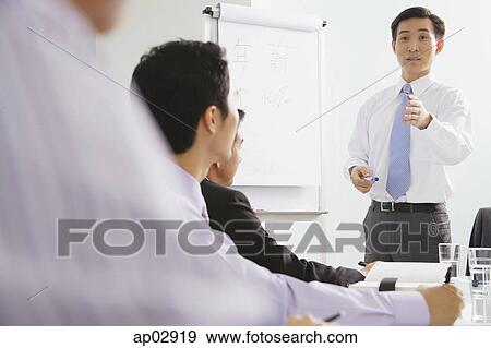 Businessman talking to other executives in a meeting View Large Photo Image Stock Photo - Businessman talking to other executives in a meeting . Fotosearch