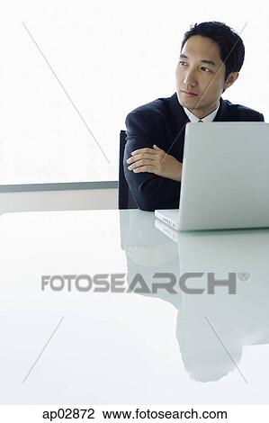 Businessman with laptop open in front of him, looking away View Large Photo Image Stock Image - Businessman with laptop open in front of him, looking away . Fotosearch