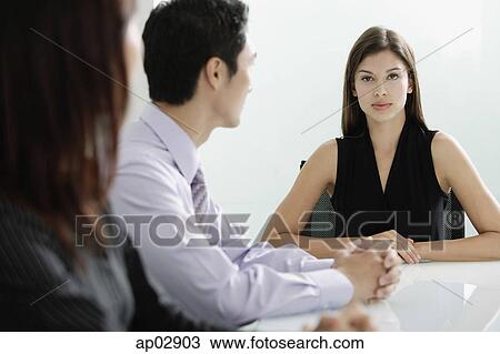Businesswoman at head of table, executives looking at her View Large Photo Image Stock Image - Businesswoman at head of table, executives looking at her . Fotosearch