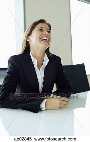 Businesswoman sitting at table, laughing View Large Photo Image Stock Photography - Businesswoman sitting at table, laughing . Fotosearch