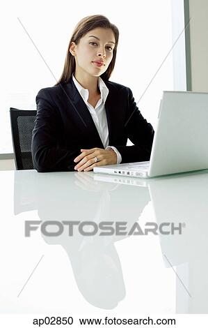 Businesswoman sitting at table, with laptop View Large Photo Image Stock Image - Businesswoman sitting at table, with laptop . Fotosearch