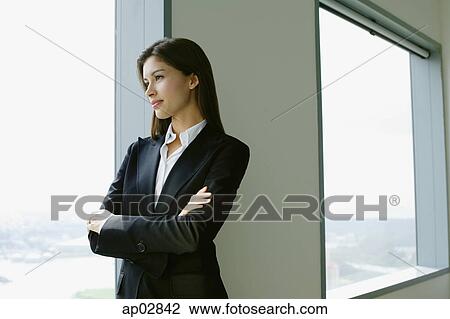 Businesswoman standing next to window in conference room, arms crossed View Large Photo Image Stock Image - Businesswoman standing next to window in conference room, arms crossed . Fotosearch