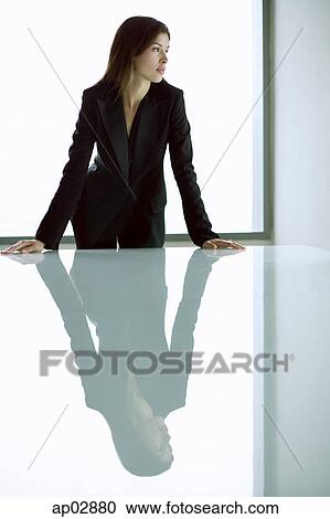 Businesswoman standing with hands on table, looking away View Large Photo Image Stock Image - Businesswoman standing with hands on table, looking away . Fotosearch