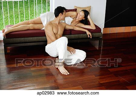 Couple at home, woman reclining on day bed, man sitting on floor View Large Photo Image Stock Image - Couple at home, woman reclining on day bed, man sitting on floor. Fotosearch