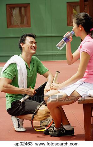 Couple at tennis court, drinking water View Large Photo Image Stock Image - Couple at tennis court, drinking water . Fotosearch
