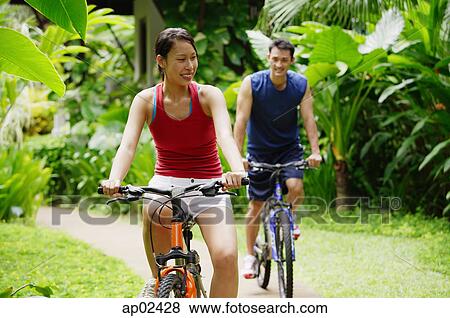 Couple cycling through a park View Large Photo Image Stock Photo - Couple cycling through a park . Fotosearch