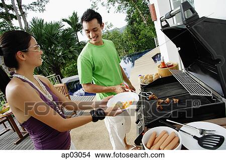 Picture - Couple grilling food on barbeque . Fotosearch